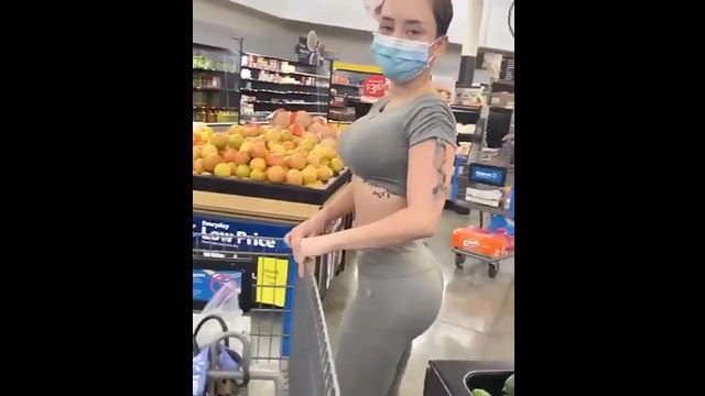 Chica caliente comprando pepino en el supermercado