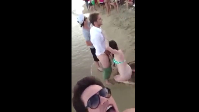 Mujer borracha dando mamada en una playa llena de gente